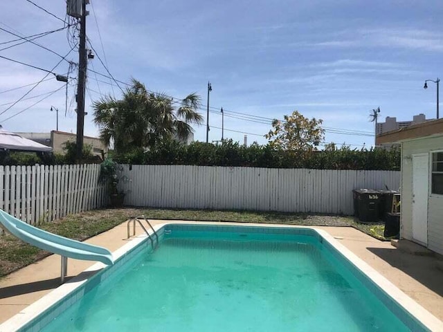 view of pool featuring a fenced backyard, a water slide, and a fenced in pool