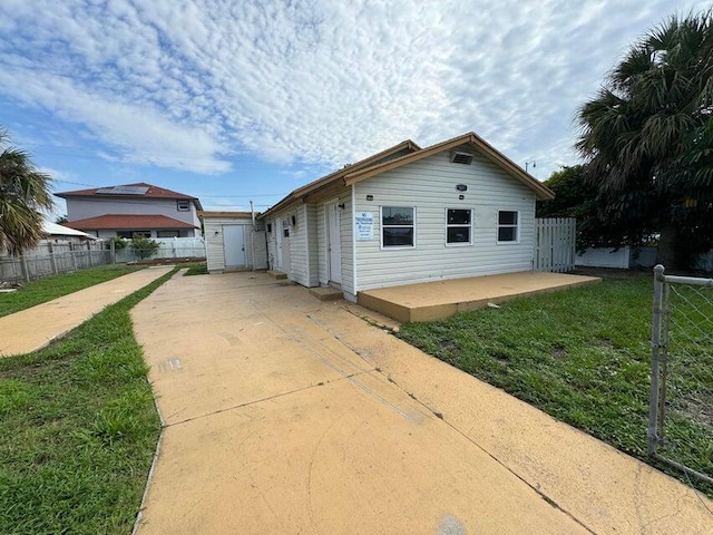 view of front facade featuring fence, driveway, a front yard, and a patio