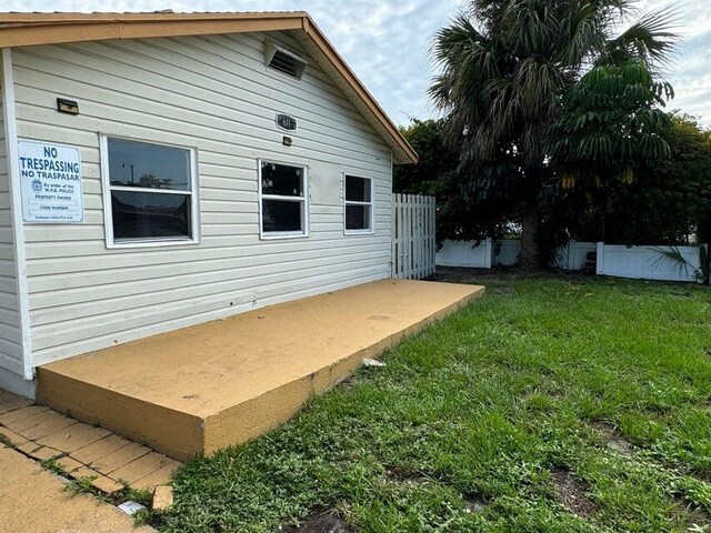 view of property exterior with fence and a lawn