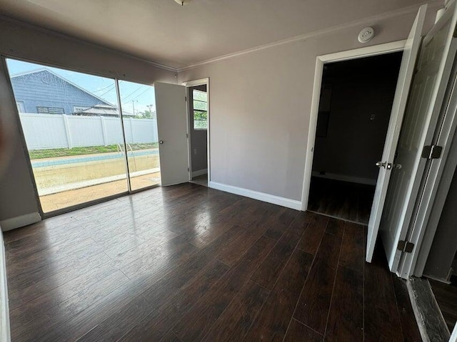 empty room featuring ornamental molding and dark hardwood / wood-style flooring