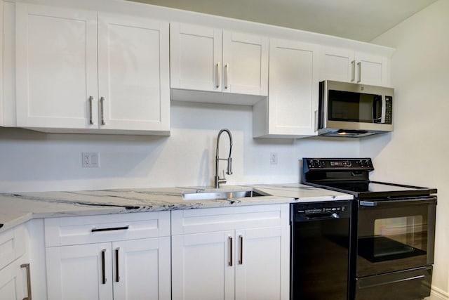 kitchen with white cabinetry, light stone counters, black appliances, and sink