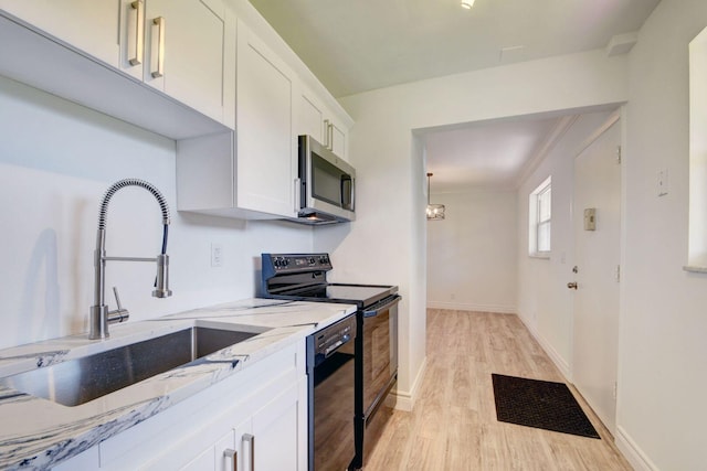 kitchen with black appliances, sink, white cabinets, light stone counters, and light hardwood / wood-style flooring