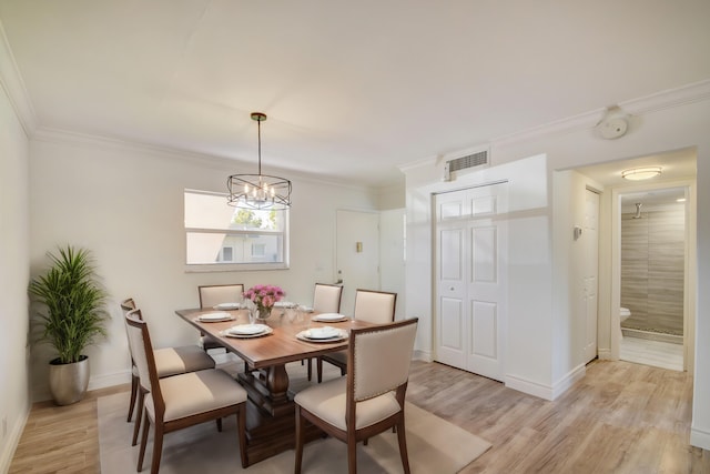 dining space featuring crown molding, light hardwood / wood-style flooring, and an inviting chandelier