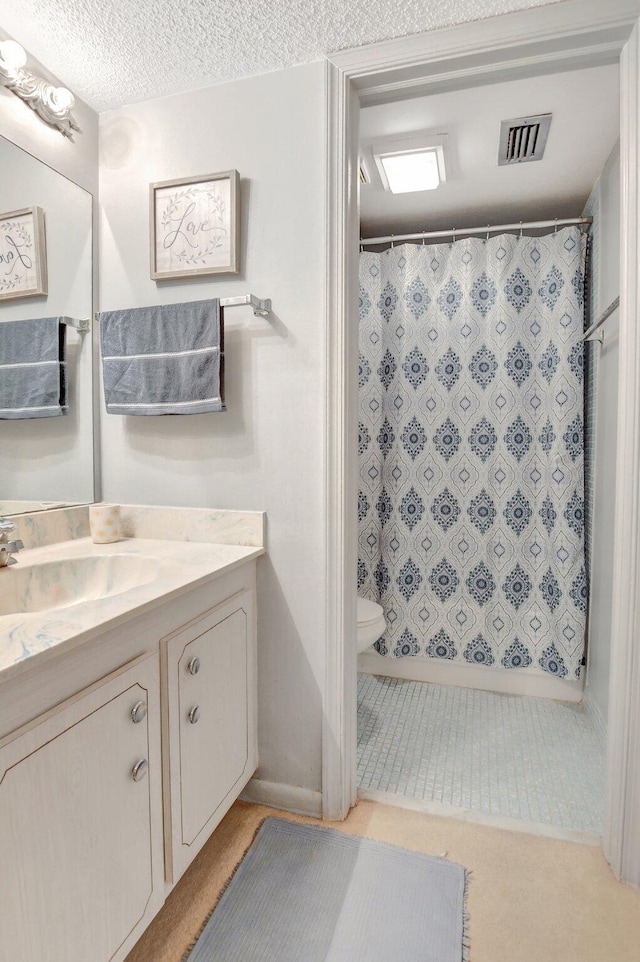 bathroom featuring toilet, walk in shower, vanity, and a textured ceiling