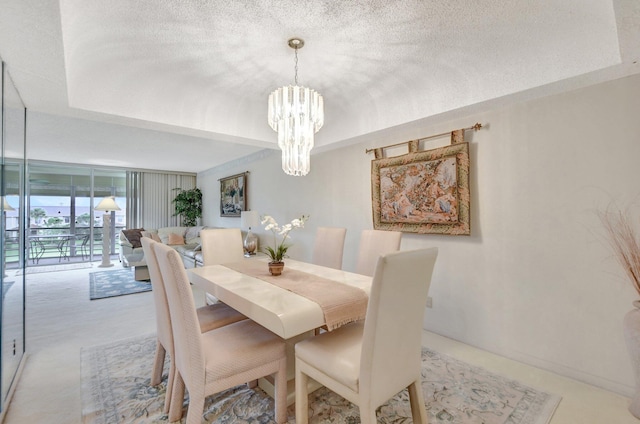 dining room with a tray ceiling, a chandelier, and a textured ceiling