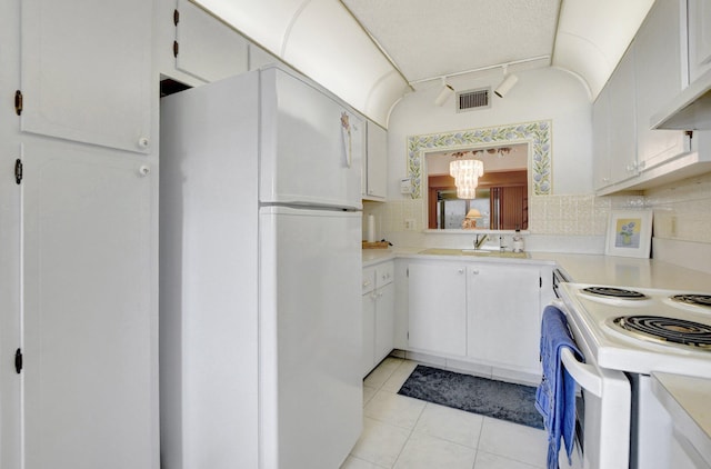 kitchen with decorative backsplash, white appliances, a notable chandelier, white cabinetry, and light tile patterned floors