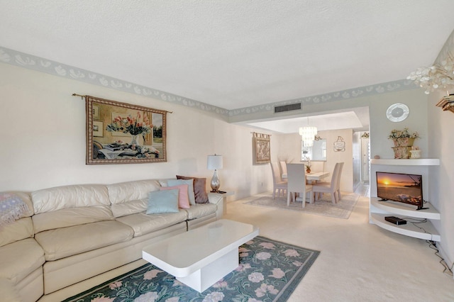 living room featuring a textured ceiling, a fireplace, a chandelier, and carpet flooring