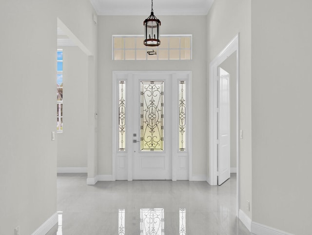 entryway with a high ceiling, a chandelier, and crown molding