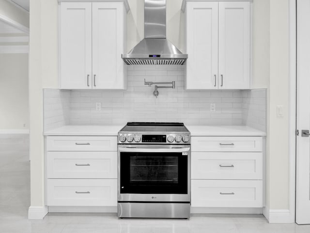 kitchen with wall chimney range hood, stainless steel stove, and white cabinets