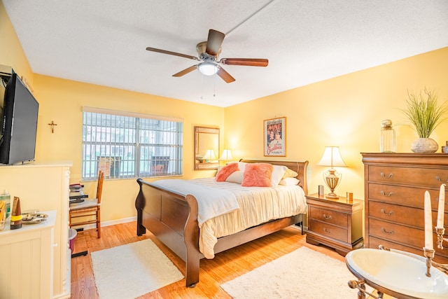 bedroom featuring ceiling fan, light hardwood / wood-style floors, and a textured ceiling