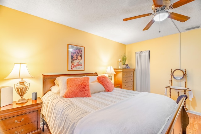 bedroom featuring ceiling fan, a textured ceiling, and light hardwood / wood-style floors