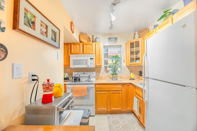 kitchen with backsplash, light tile patterned floors, white appliances, and rail lighting