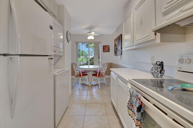 kitchen featuring white refrigerator, white cabinetry, light tile patterned floors, stove, and premium range hood