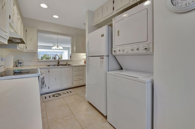 laundry area with stacked washing maching and dryer, sink, a chandelier, and light tile patterned floors