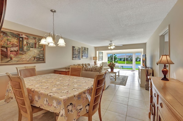 tiled dining area with a textured ceiling and ceiling fan with notable chandelier