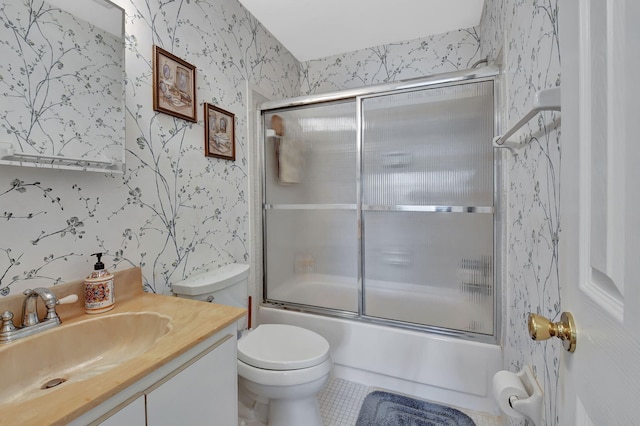 full bathroom with vanity, bath / shower combo with glass door, toilet, and tile patterned floors