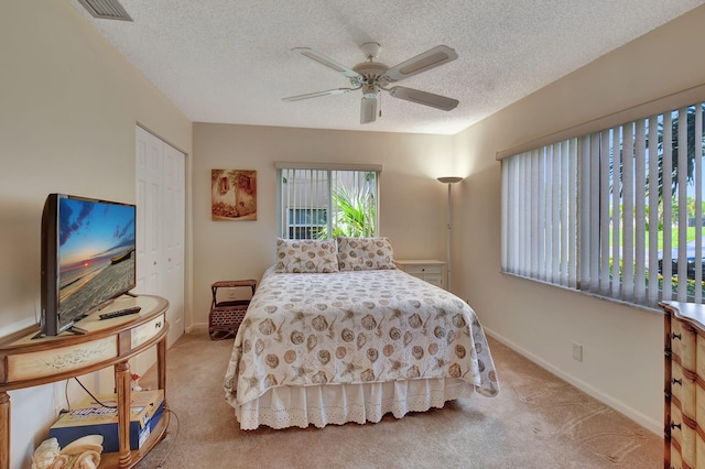 bedroom with a closet, ceiling fan, light carpet, and a textured ceiling