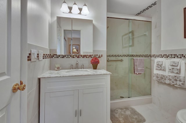 bathroom featuring tile walls, vanity, a shower with shower door, and toilet