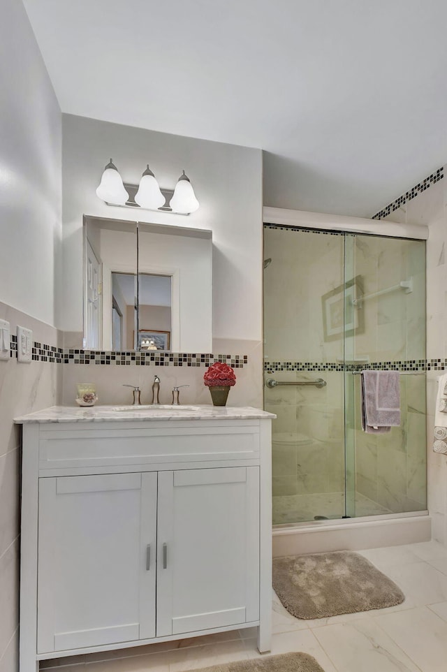 bathroom with a shower with door, tile walls, and vanity