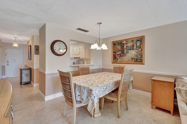 dining room with an inviting chandelier, a textured ceiling, and light tile patterned floors