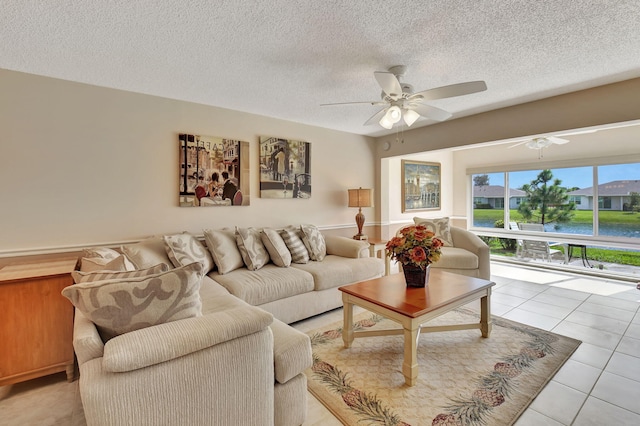 tiled living room with a textured ceiling, a water view, and ceiling fan