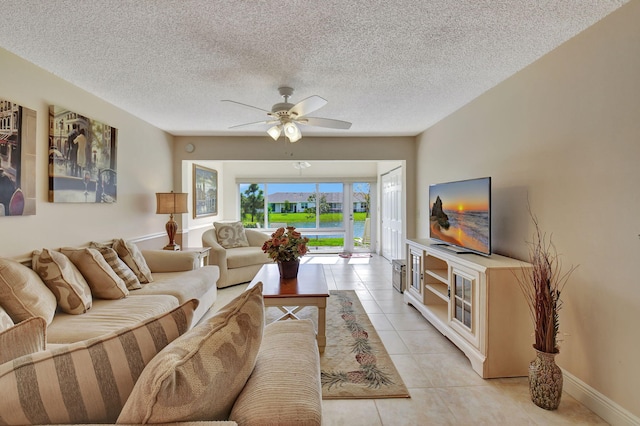 living room with ceiling fan, a textured ceiling, and light tile patterned floors