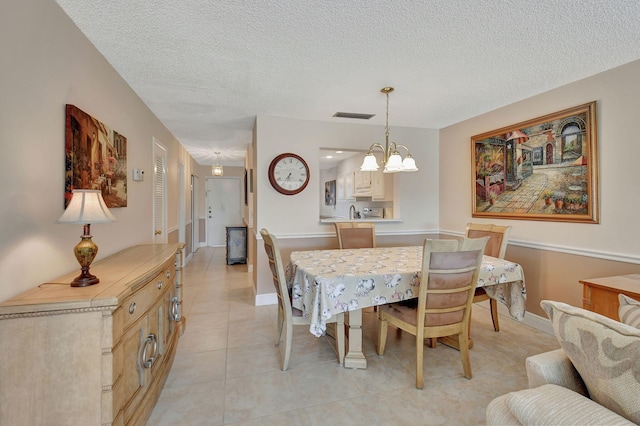 tiled dining space featuring a notable chandelier and a textured ceiling