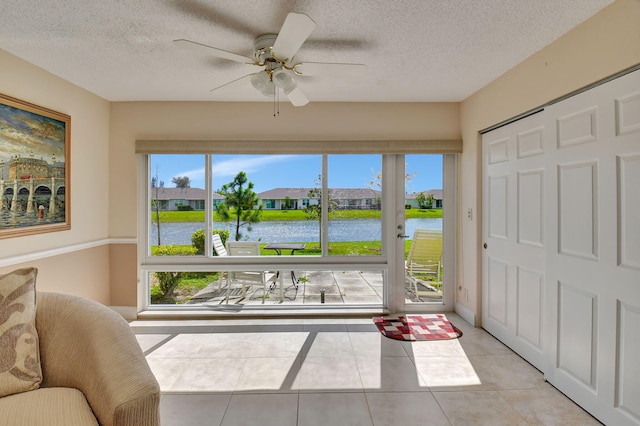 sunroom / solarium featuring a water view and ceiling fan