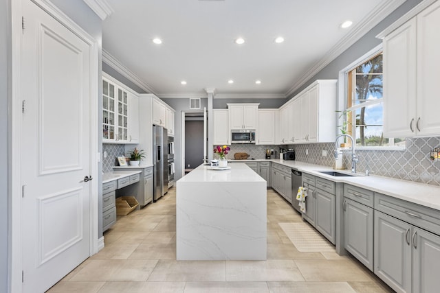 kitchen with gray cabinets, sink, stainless steel appliances, a center island, and white cabinetry