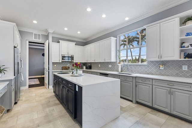 kitchen with sink, a center island with sink, white cabinetry, appliances with stainless steel finishes, and decorative backsplash