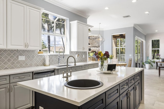 kitchen with crown molding, backsplash, dishwasher, hanging light fixtures, and white cabinets