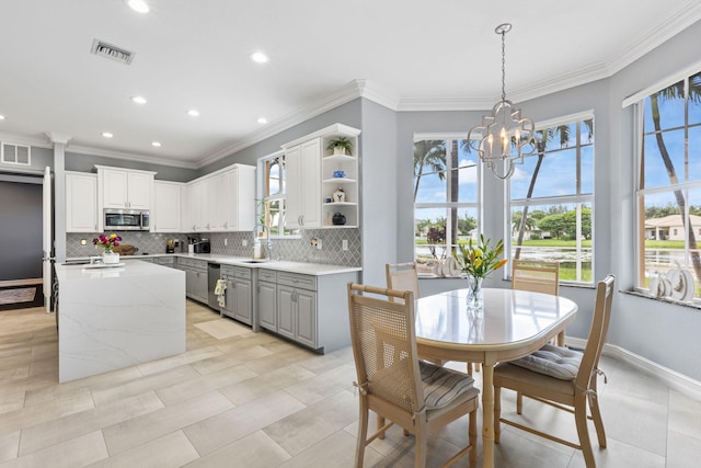 kitchen with hanging light fixtures, white cabinetry, gray cabinets, stainless steel appliances, and decorative backsplash