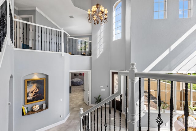 staircase with high vaulted ceiling, crown molding, and a chandelier