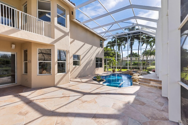 view of swimming pool featuring glass enclosure, a patio, and a jacuzzi