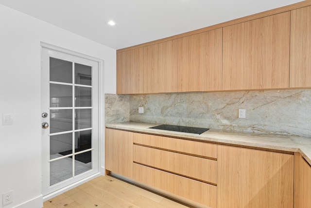 kitchen featuring tasteful backsplash, black electric cooktop, light brown cabinets, and light wood-type flooring