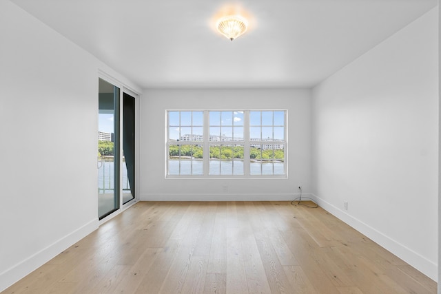 unfurnished room with a water view and light wood-type flooring