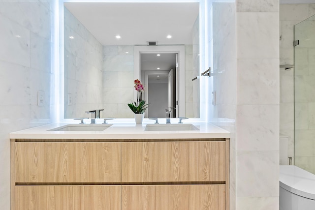 bathroom featuring tile walls, vanity, a shower with door, and toilet