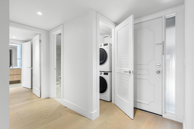 laundry area with stacked washing maching and dryer and light wood-type flooring