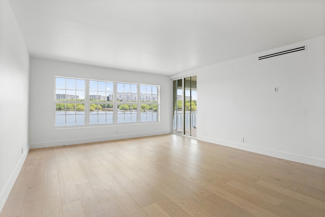 unfurnished room featuring a water view and light hardwood / wood-style floors