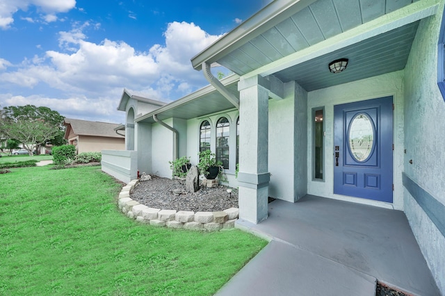 entrance to property with covered porch and a yard