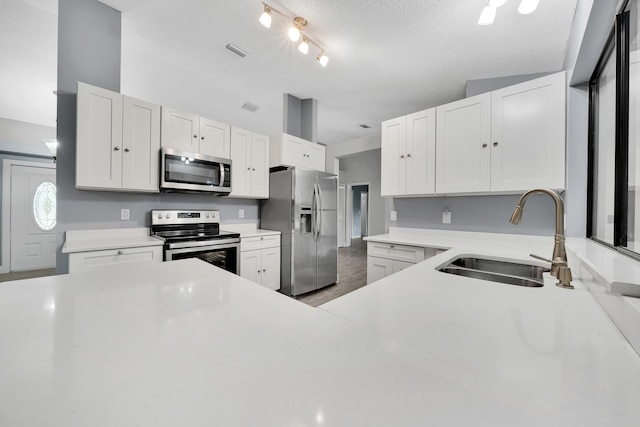 kitchen featuring white cabinetry, sink, a textured ceiling, and appliances with stainless steel finishes