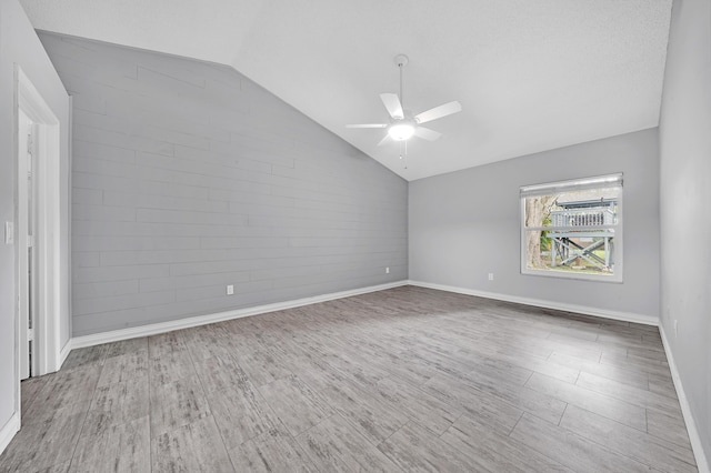 spare room featuring a textured ceiling, light hardwood / wood-style floors, ceiling fan, and lofted ceiling