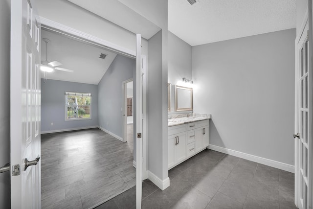 bathroom featuring tile patterned floors, a textured ceiling, vanity, ceiling fan, and lofted ceiling