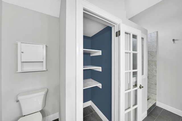 bathroom featuring toilet, built in shelves, a textured ceiling, and tile patterned floors