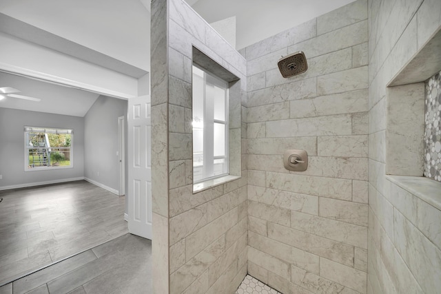 bathroom with a tile shower, vaulted ceiling, and ceiling fan