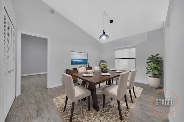 dining area with light wood-type flooring and high vaulted ceiling