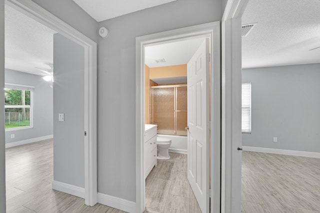 hall featuring light wood-type flooring and a textured ceiling