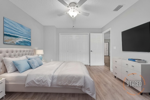 bedroom with ceiling fan, a closet, a textured ceiling, and light wood-type flooring