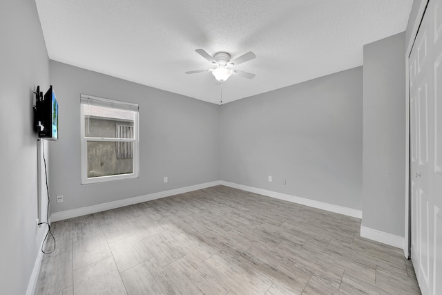 unfurnished room with ceiling fan and a textured ceiling