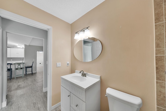 bathroom featuring a textured ceiling, vanity, lofted ceiling, and toilet